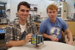 Jacob Leiken and Mckenna Cisler (L-R), team project leaders for the Brown University EQUiSAT, show a true-scale mock-up model of the earth orbiting satellite, a 10cm cube. (Photo: Michael Bilow)